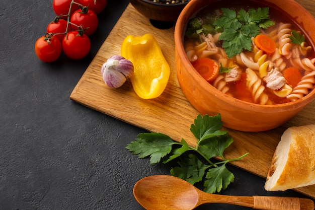 Piatto laici broccoli carote e zuppa di fusilli in una ciotola con pane e cucchiaio di legno