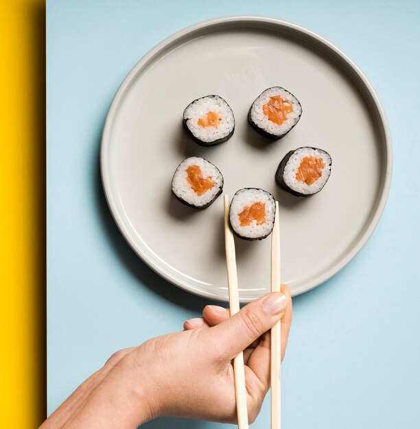 Piatto minimalista con involtini di sushi e bacchette