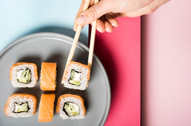 Piatto minimalista con involtini di sushi e bacchette