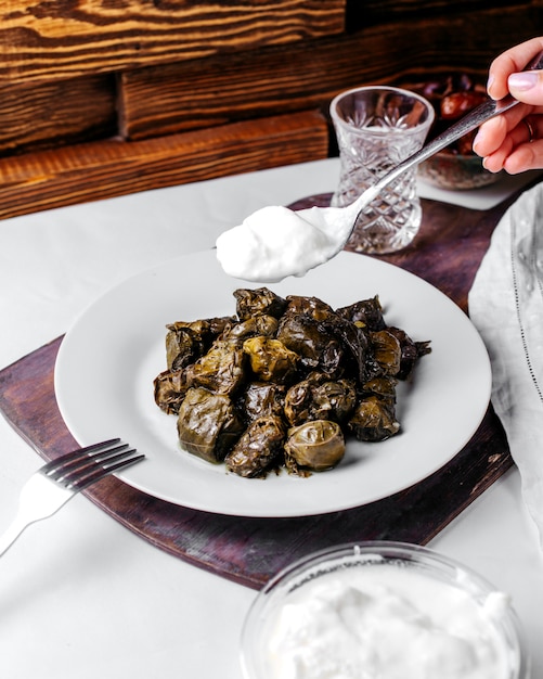 Piatto orientale saporito della carne di dolma di vista frontale con yogurt bianco dentro il piatto bianco sullo scrittorio bianco