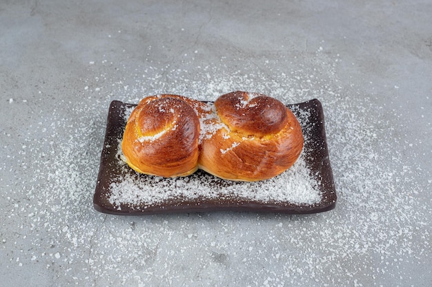 Piatto ricoperto di polvere di cocco con panini dolci sul tavolo di marmo.