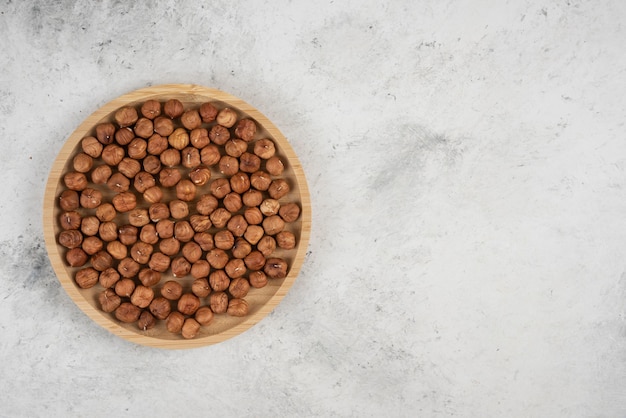 Piatto rotondo di gherigli di nocciola organici sul tavolo di marmo.