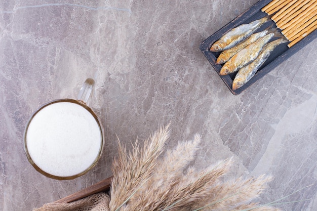 Piatto scuro di snack e birra schiumosa sulla superficie di marmo. Foto di alta qualità