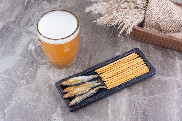 Piatto scuro di snack e birra schiumosa sulla superficie di marmo. Foto di alta qualità