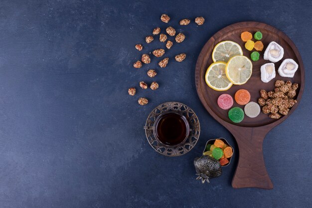 Piatto snack in legno con caramelle e un bicchiere di tè