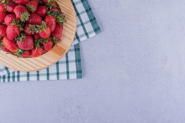 Piatto su una tovaglia piegata con un mucchio di fragole su fondo marmo. Foto di alta qualità