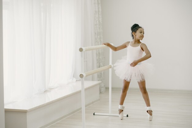 Piccola ballerina sveglia in costume da balletto rosa. Il bambino in scarpe da punta sta ballando nella stanza. Kid in classe di danza.