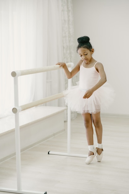 Piccola ballerina sveglia in costume da balletto rosa. Il bambino in scarpe da punta sta ballando nella stanza. Kid in classe di danza.