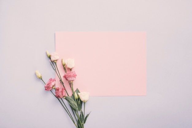 Piccola carta con fiori di rosa sul tavolo luminoso