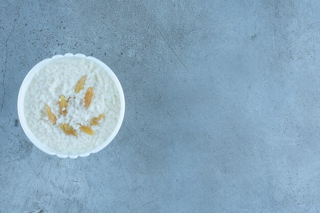 Piccola ciotola di farina d'avena condita con una manciata di uvetta su marmo.