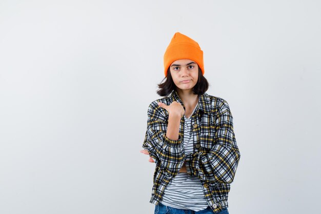 Piccola donna che indica se stessa in berretto con giacca a t-shirt e sembra orgogliosa