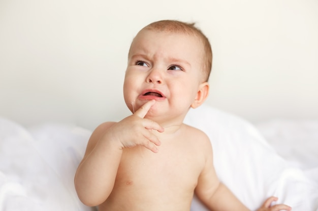 Piccola donna piacevole sveglia del bambino che grida menzogne con sua mamma sul letto a casa.