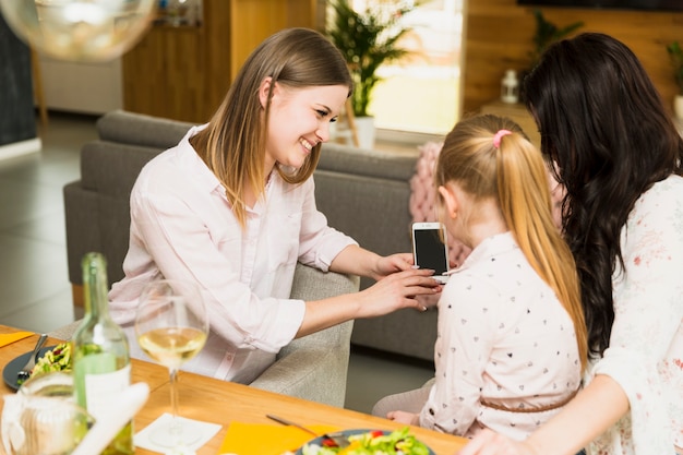 Piccola figlia che si siede sulle ginocchia della madre