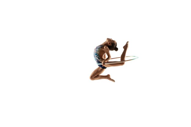 Piccola ginnasta femminile flessibile isolata sulla parete bianca