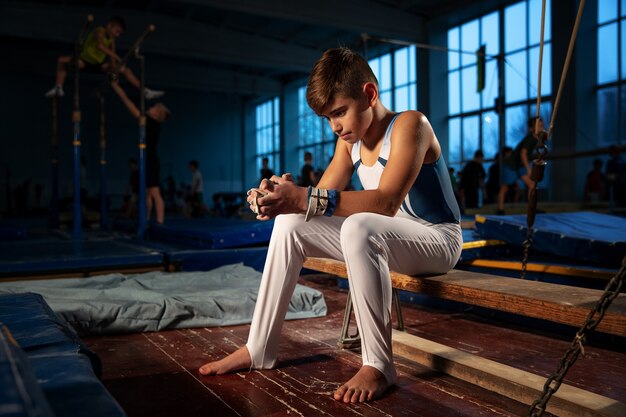 Piccola ginnasta maschio che si allena in palestra, flessibile e attiva