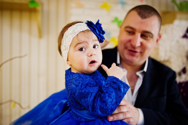 Piccola neonata sveglia al vestito blu sulle mani del padre