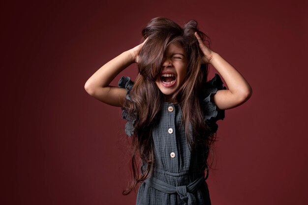 Piccola ragazza asiatica che urla e si tiene le mani tra i capelli