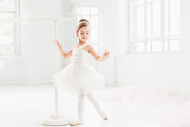 Piccola ragazza ballerina in un tutu. Bambino adorabile che balla balletto classico in uno studio bianco.