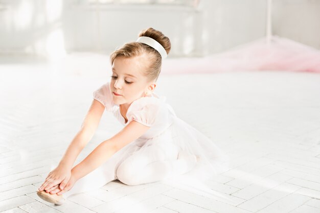 Piccola ragazza ballerina in un tutu. Bambino adorabile che balla balletto classico in uno studio bianco.