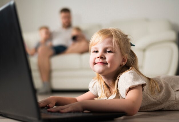 Piccola ragazza bionda che gioca su un computer portatile