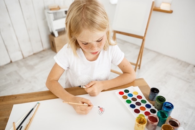 Piccola ragazza bionda sveglia occupata e concentrata