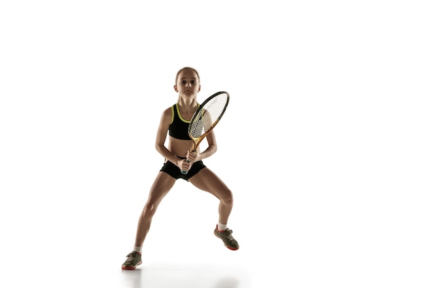 Piccola ragazza caucasica giocando a tennis isolato sul muro bianco