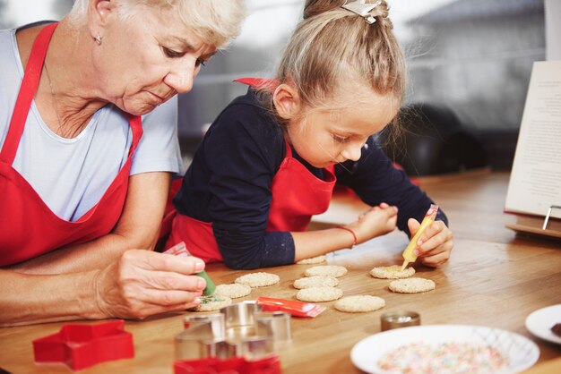 Piccola ragazza che decora i biscotti con sua nonna