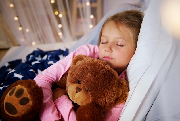 Piccola ragazza che dorme con l'orsacchiotto