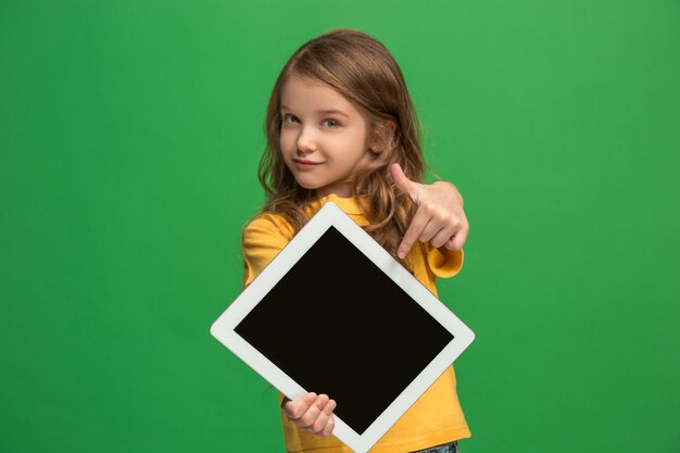 Piccola ragazza divertente con la compressa sulla parete verde dello studio