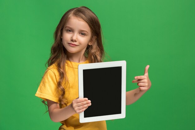 Piccola ragazza divertente con tablet su studio verde