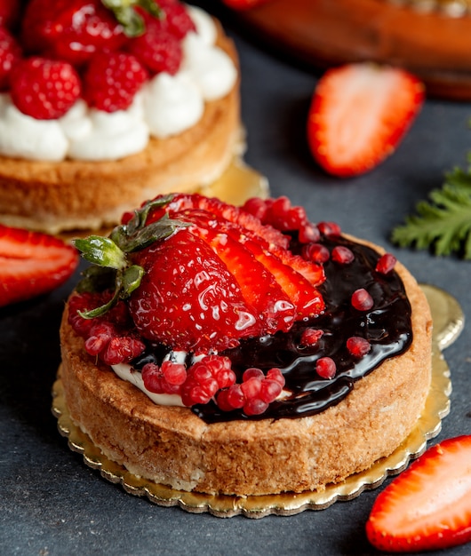 Piccola torta rotonda decorata con crema al cioccolato e fragole