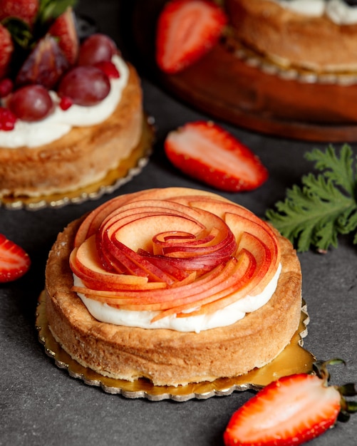 Piccola torta rotonda decorata con fette di crema e mela rossa