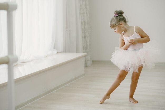 Piccole ballerine carine in costume da balletto rosa. Il bambino in scarpe da punta sta ballando nella stanza. Kid in classe di danza.