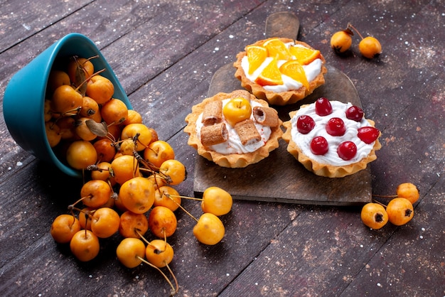 piccole deliziose torte con crema di frutta a fette e ciliegie fresche gialle su legno marrone, torta di frutta fresca biscotto amarena