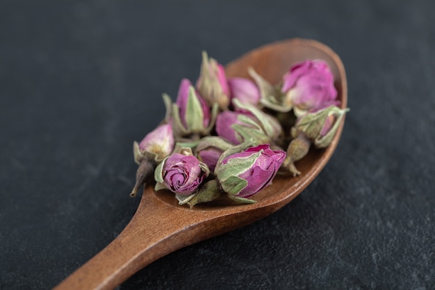 Piccole rose in erba sul cucchiaio di legno.