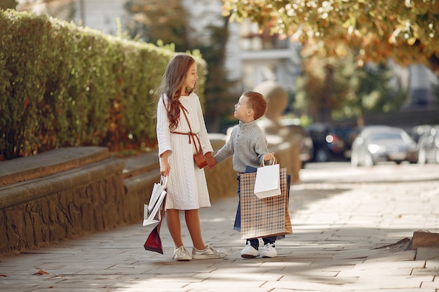 Piccoli bambini svegli con il sacchetto della spesa in una città