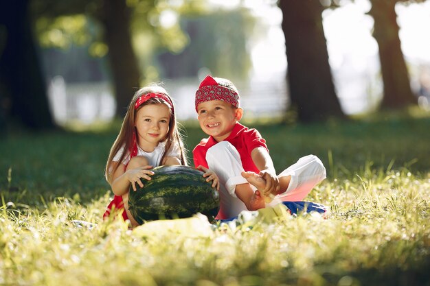 Piccoli bambini svegli con le angurie in un parco