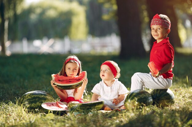 Piccoli bambini svegli con le angurie in un parco