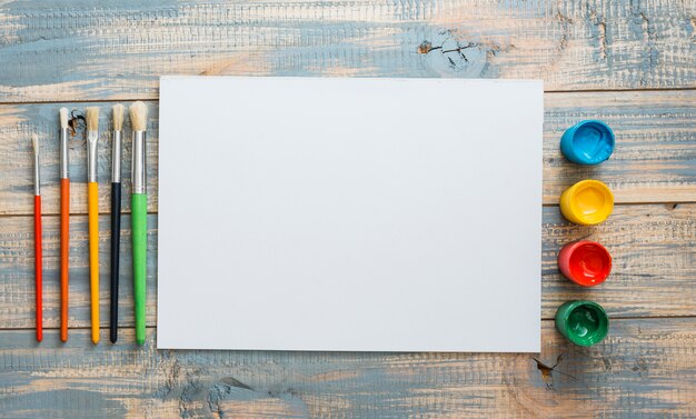 Piccoli contenitori e pennelli per acquerello con lenzuolo bianco
