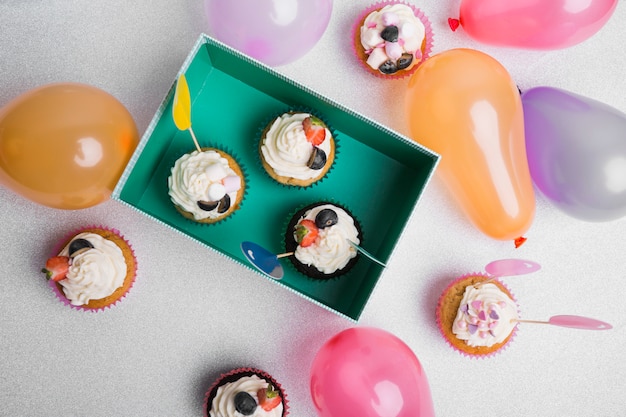 Piccoli cupcakes con palloni ad aria sul tavolo