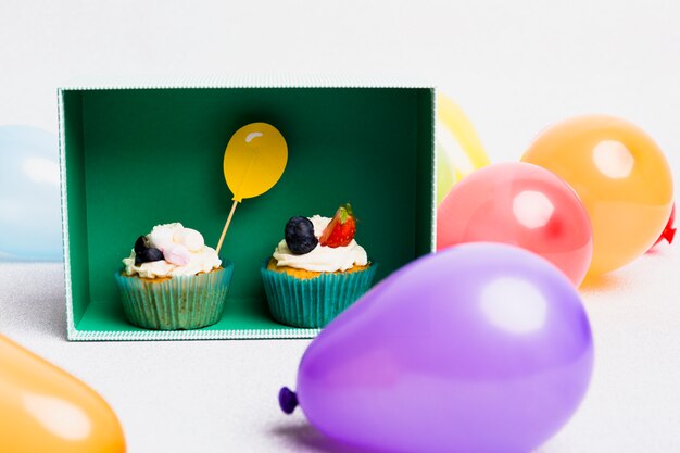 Piccoli cupcakes in scatola con palloni ad aria