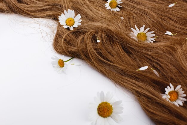 Piccoli fiori bianchi si trovano sui riccioli di capelli castani