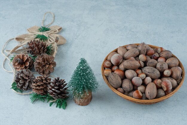 Piccolo albero di Natale con cesto di noci su sfondo marmo. Foto di alta qualità