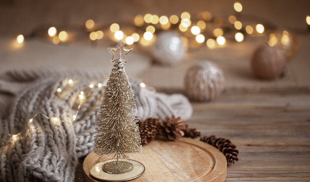Piccolo albero di Natale lucido decorativo si chiuda su uno sfondo di luci sfocate con bokeh in colori caldi.