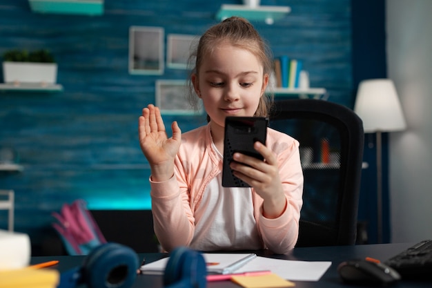 Piccolo bambino che saluta un amico remoto durante la conferenza della riunione di videochiamata online