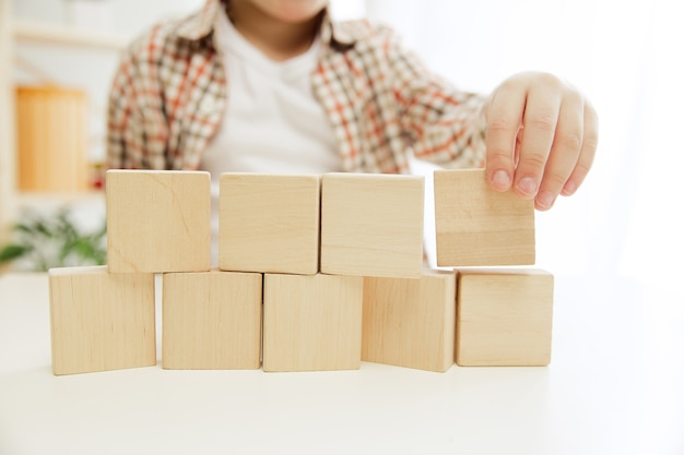 Piccolo bambino seduto sul pavimento. Bel ragazzo che palying con cubetti di legno a casa.