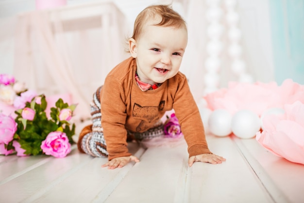 Piccolo bambino si siede tra i fiori rosa sul pavimento