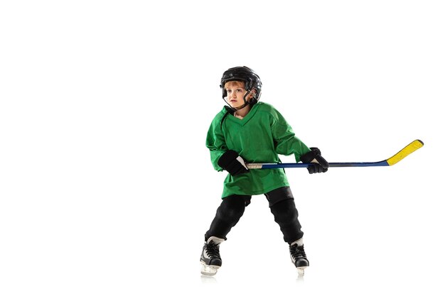 Piccolo giocatore di hockey con il bastone sul campo da ghiaccio, muro bianco. Sportsboy che indossa attrezzatura e casco, pratica, allenamento. Concetto di sport, stile di vita sano, movimento, movimento, azione.