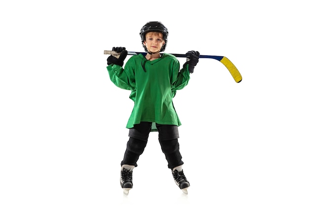 Piccolo giocatore di hockey con il bastone sul campo da ghiaccio, parete bianca dello studio