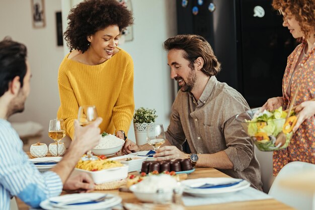 Piccolo gruppo di giovani felici che si divertono durante l'ora di pranzo a casa